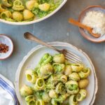 Overhead view of pasta con broccoli served in a shallow bowl, with shell pasta coated in a creamy mashed broccoli sauce and topped with grated cheese and black pepper.