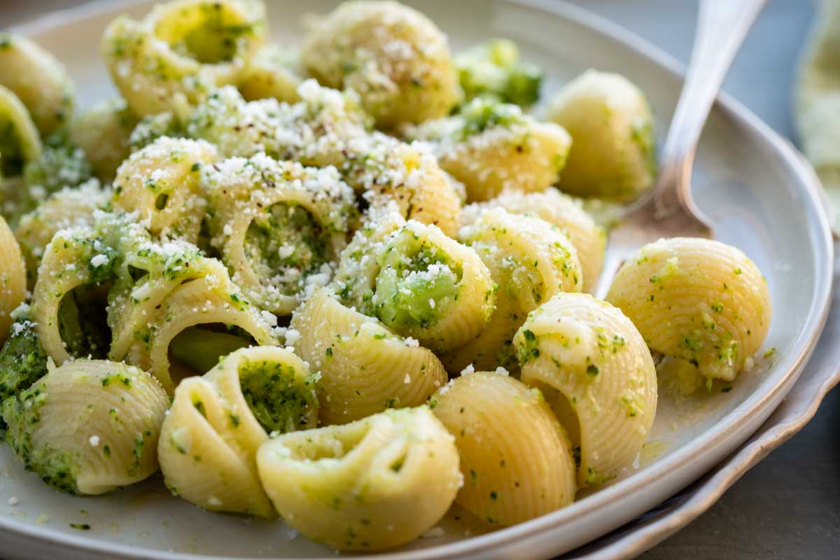 Close up of short pasta with broccoli sauce, sprinkled with pecorino cheese.