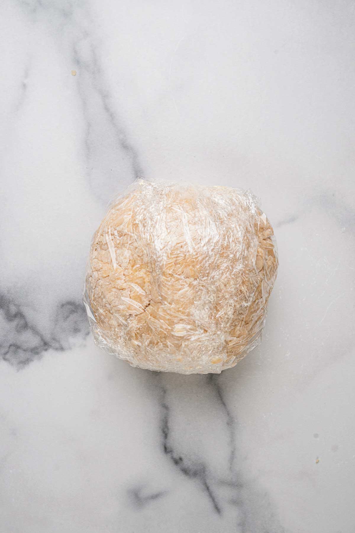 Cannoli dough wrapped in plastic wrap to rest.