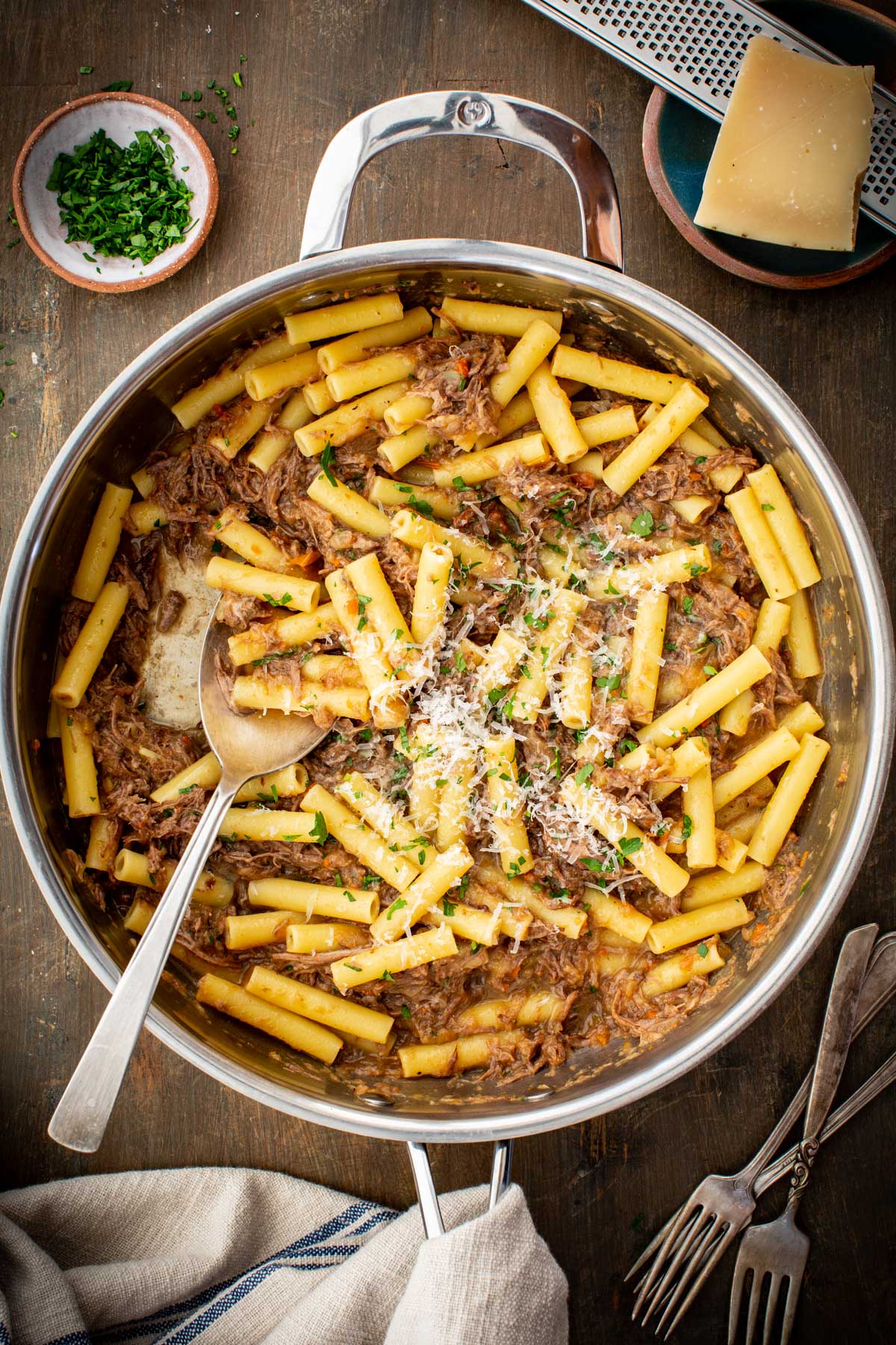 Ziti pasta tossed with slow cooked beef and onion Genovese sauce, topped with grated cheese and parsley in a skillet.