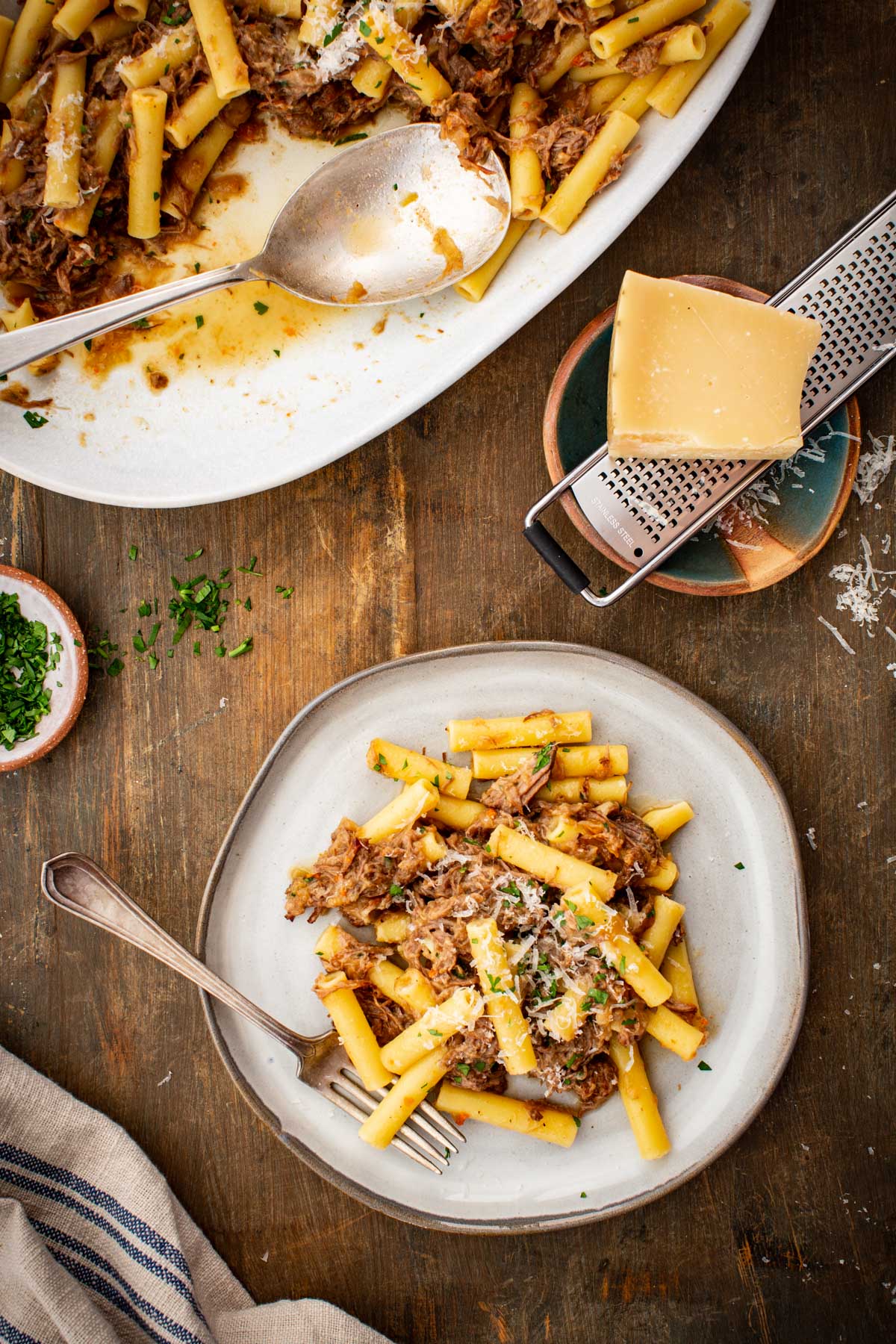 Top view of a platter of pasta alla genovese served onto a white dish next to a cheese grater.