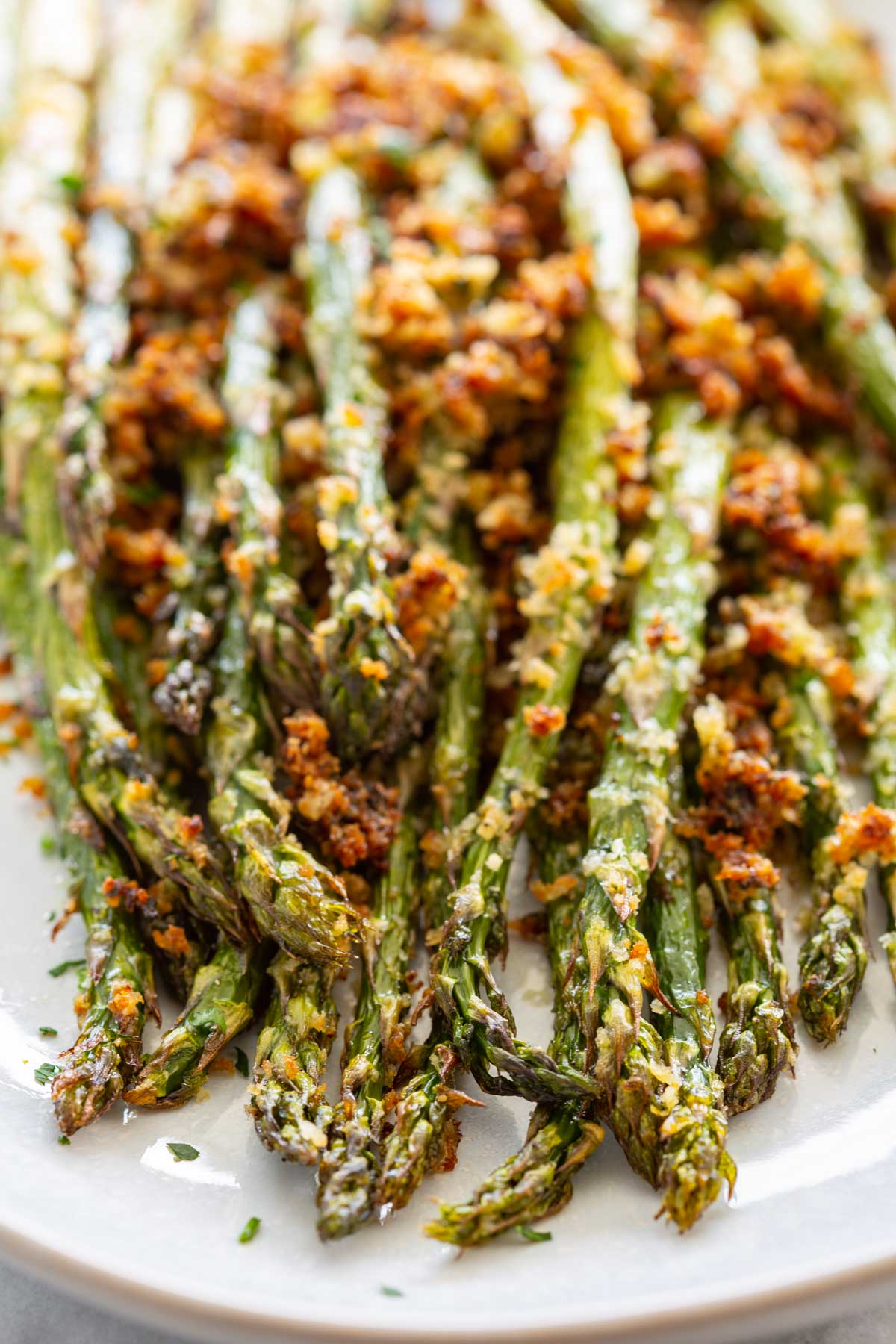 Close-up of roasted asparagus tips showing the deeply caramelized, crunchy parmesan panko topping with golden-brown breadcrumbs and melted cheese.