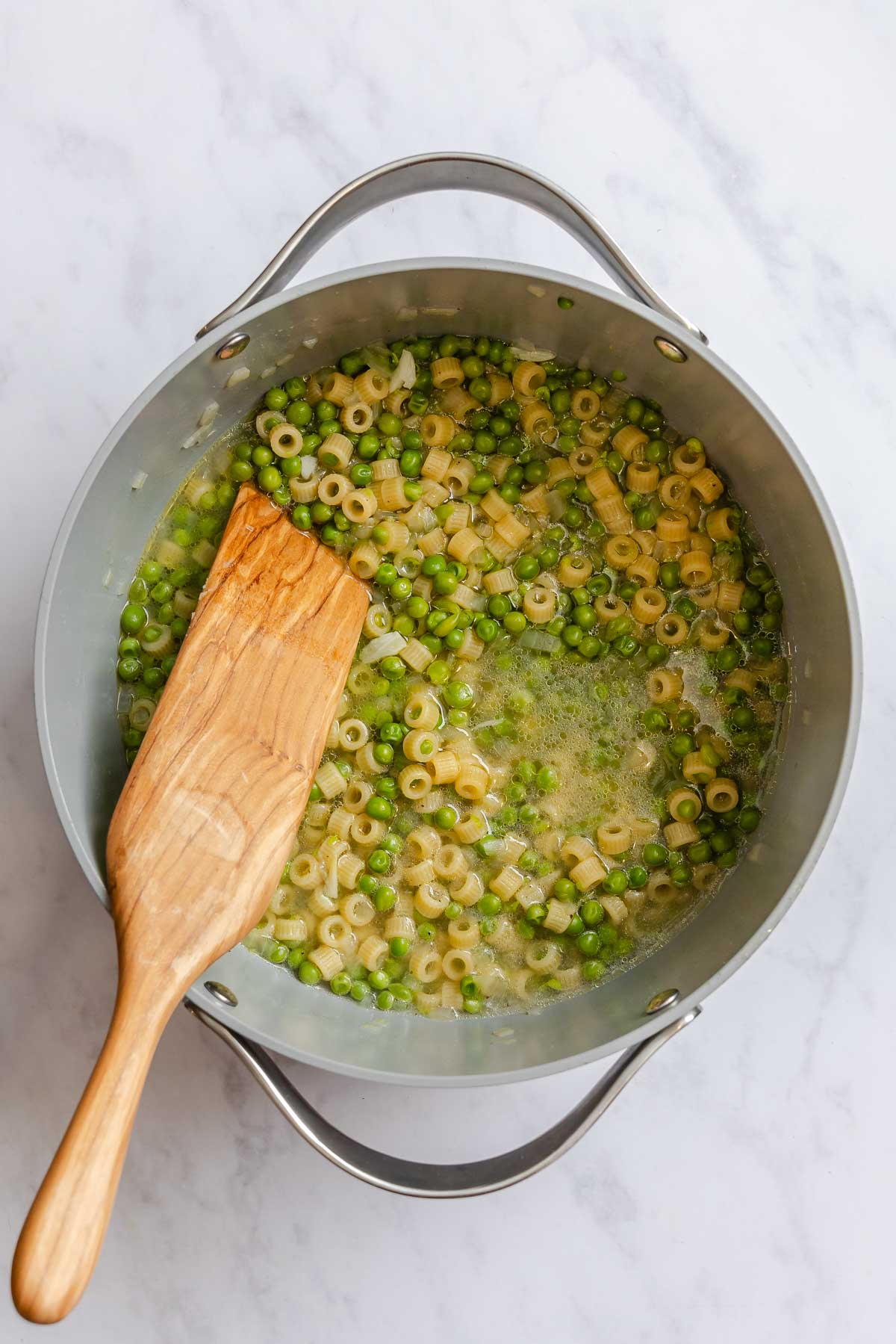 Ditalini pasta and peas cooked in a gray pot after liquid has reduced.