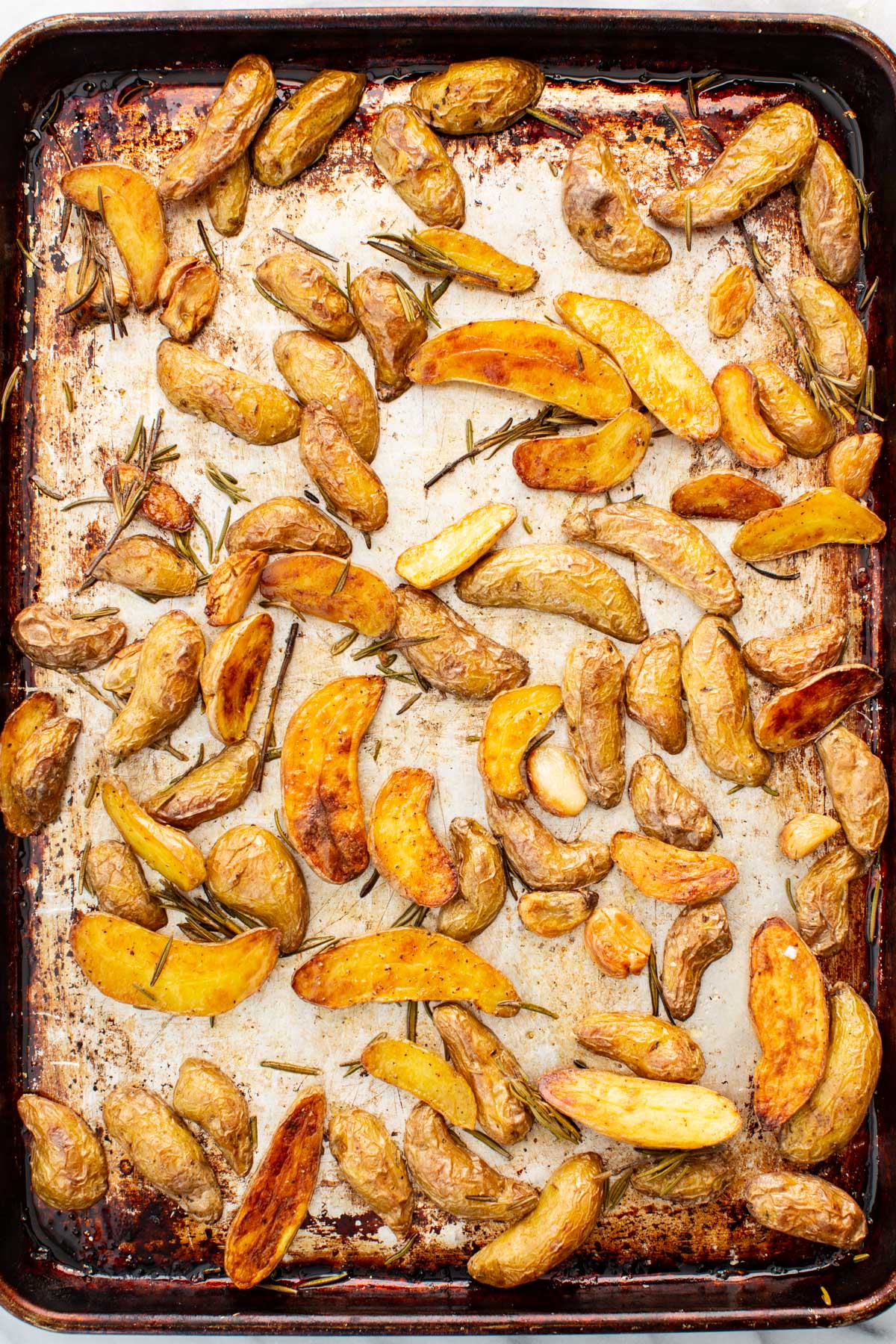 Fingerling potatoes after roasting, golden brown all around in a sheet pan.