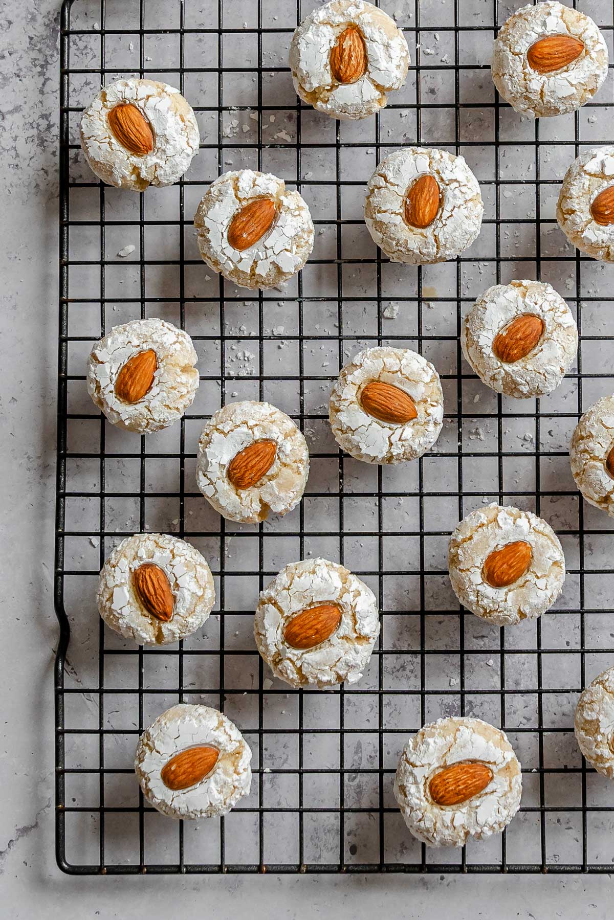 Overhead shot of Italian almond cookies over a cookie tray in a gray marble background.