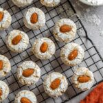 Overhead shot of Sicilian almond cookies over a cookie tray next to powdered sugar and a red kitchen towel.