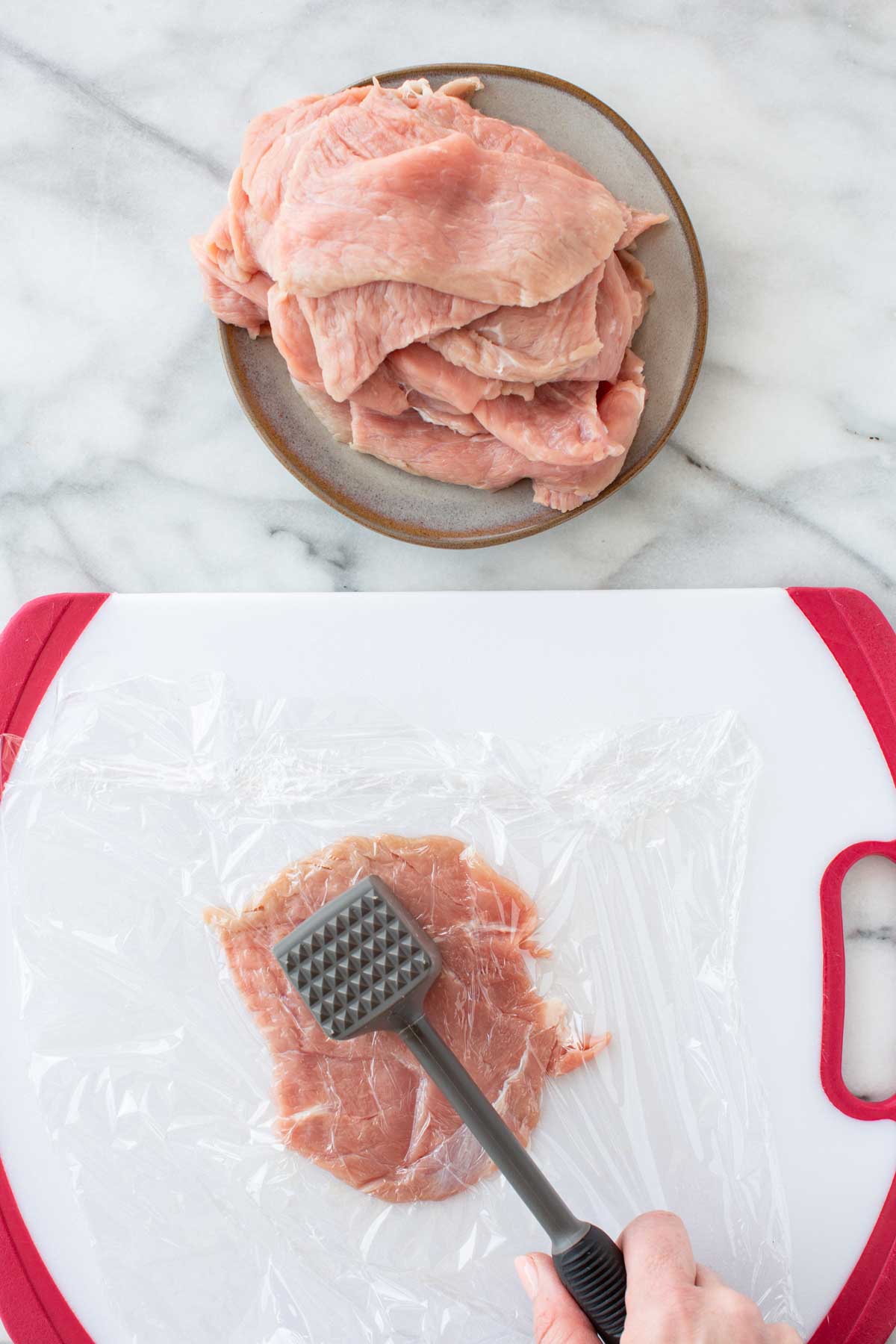Two-panel photo showing raw veal cutlets stacked on a plate (top), and a single cutlet being pounded thin under plastic wrap with a meat mallet on a white cutting board (bottom).