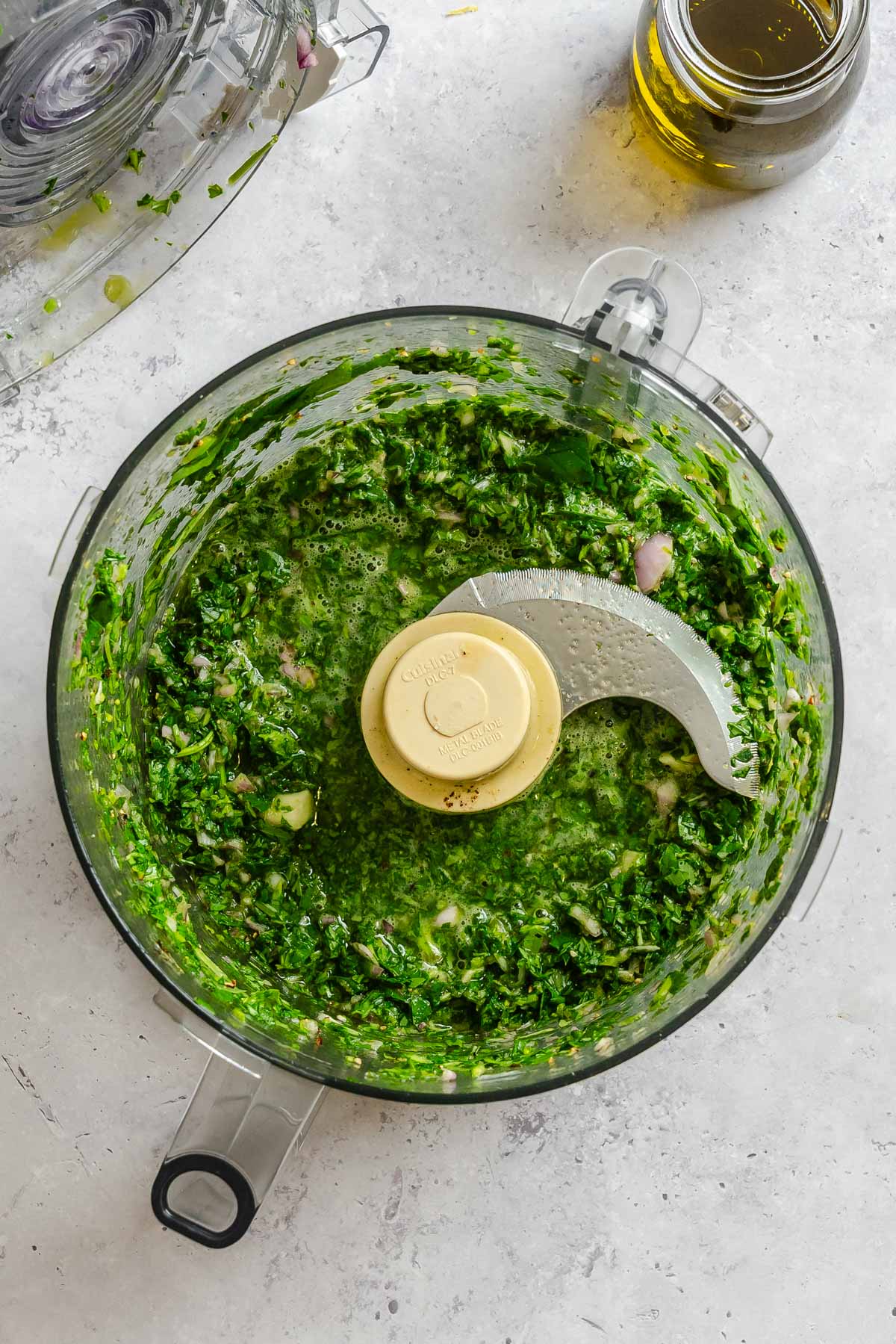 Roughly chopped basil, shallot, and garlic in a food processor after the first pulses.