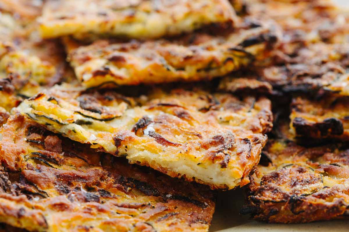 Close-up of scarpaccia pieces showing the thin, crisp layers of zucchini and onion with a soft interior and browned, blistered top.