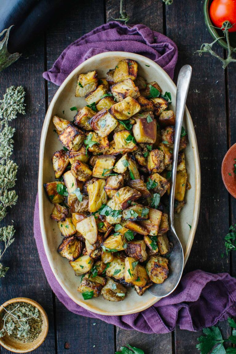 Overhead shot of roasted eggplant garnished with parsley on an oval platter.