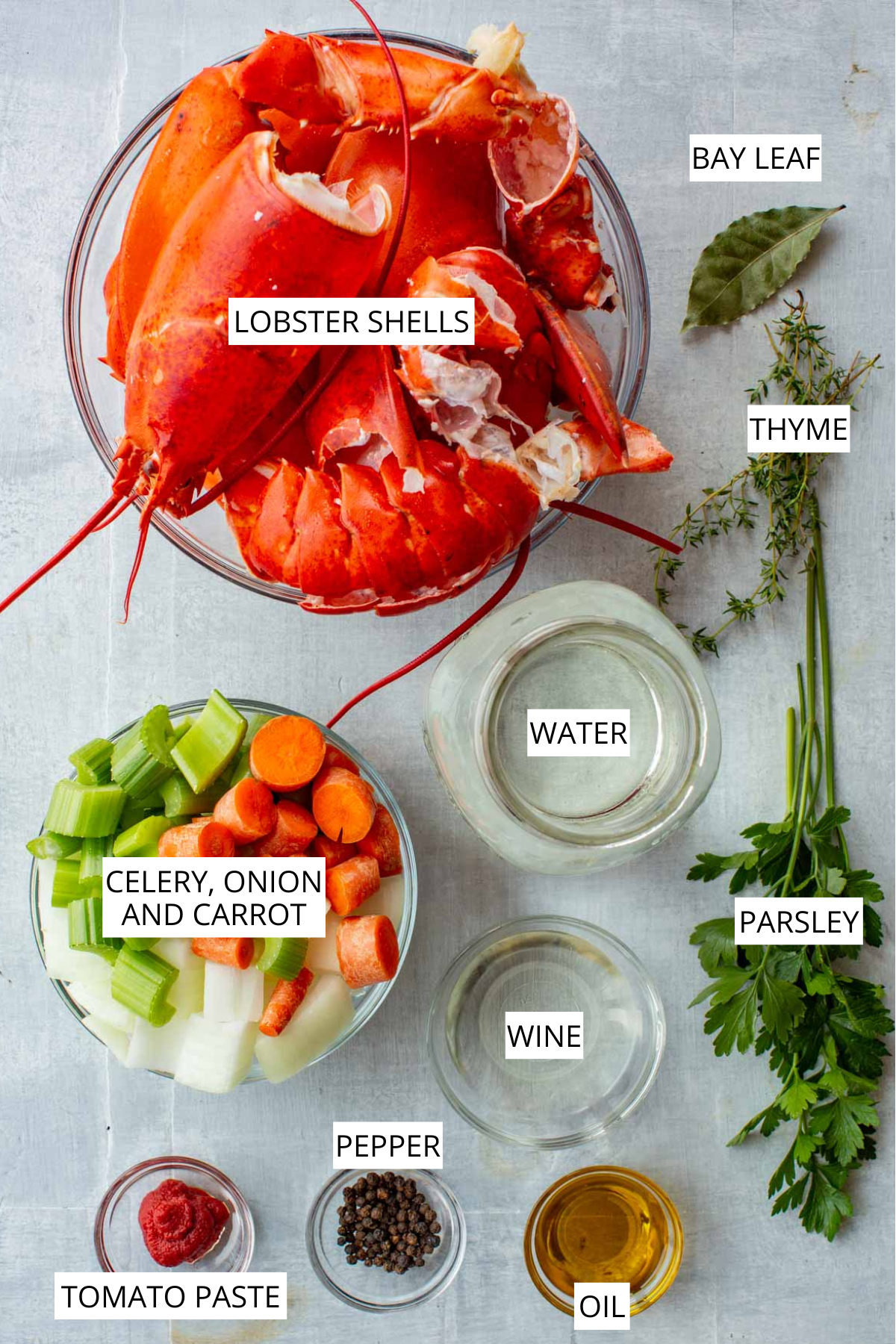 Labeled ingredients for lobster stock, including lobster shells, celery, onion, and carrot, water, wine, tomato paste, black pepper, oil, bay leaf, thyme, and parsley.