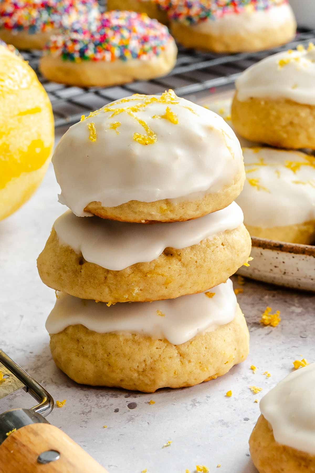 A lemon ricotta cookie broken in half, revealing a soft, tender crumb, stacked on another glazed cookie half.