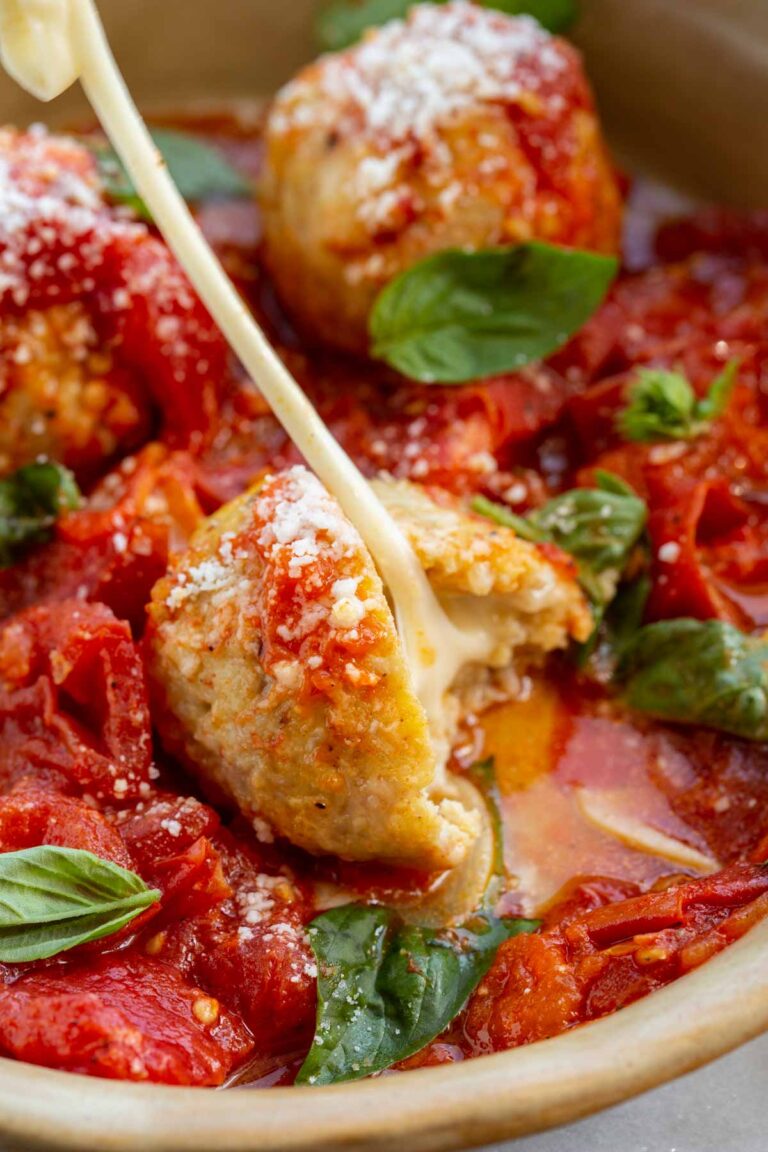 Close-up of a stuffed chicken meatball with melted mozzarella oozing out of the center.