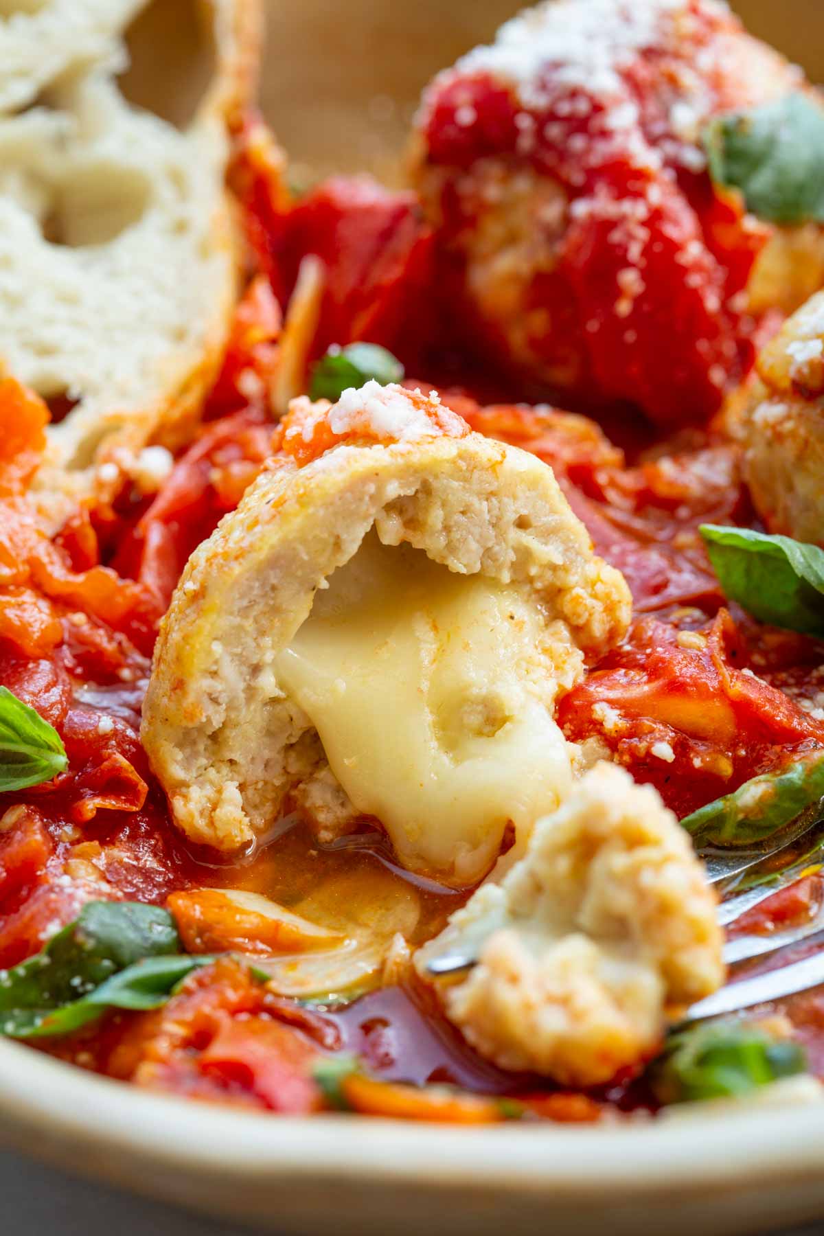 Close-up of a stuffed chicken meatball sliced in half with melted mozzarella oozing out.