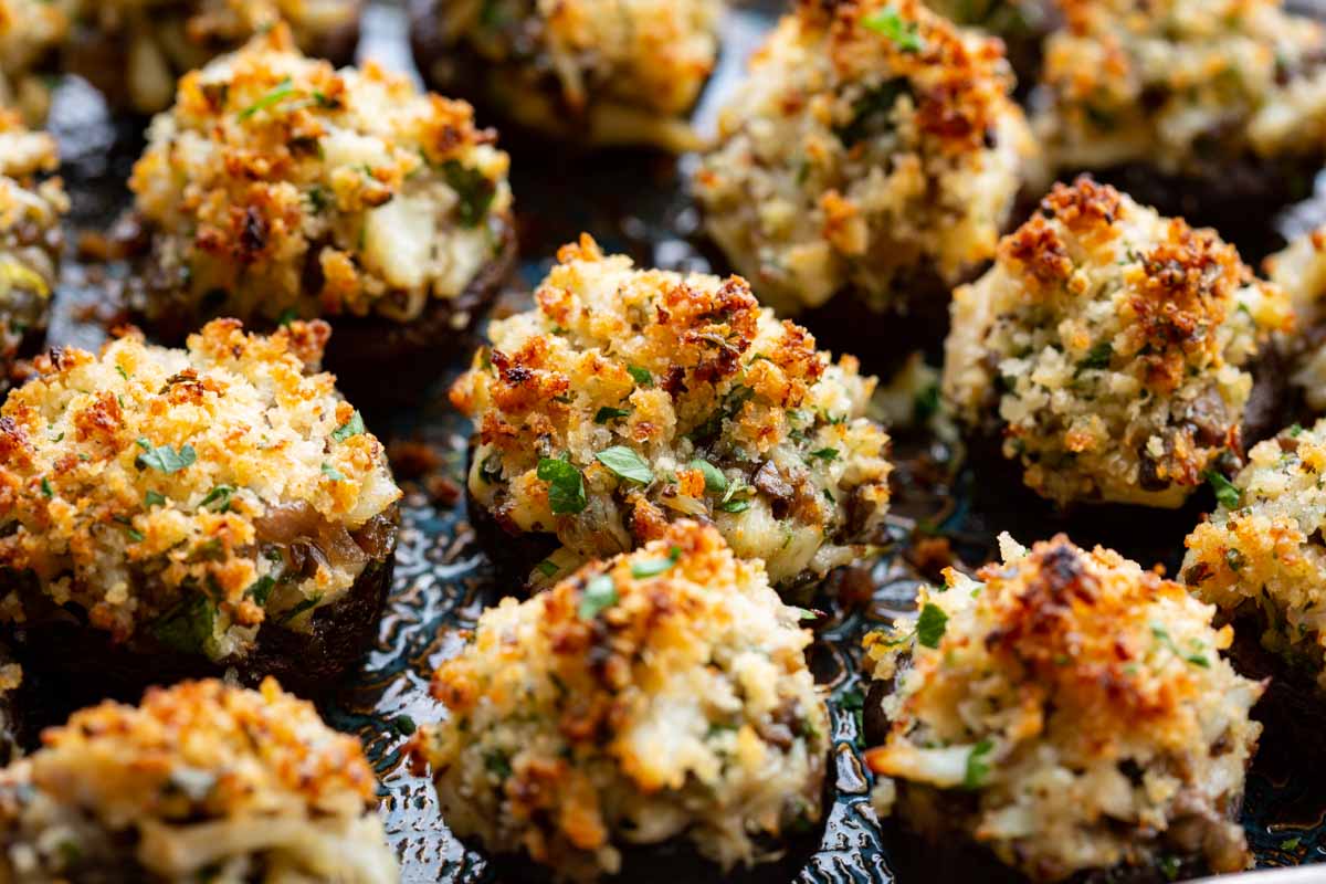 Close-up of crab stuffed mushrooms with a toasted panko and parmesan crust, chopped parsley, and chunks of lump crab.